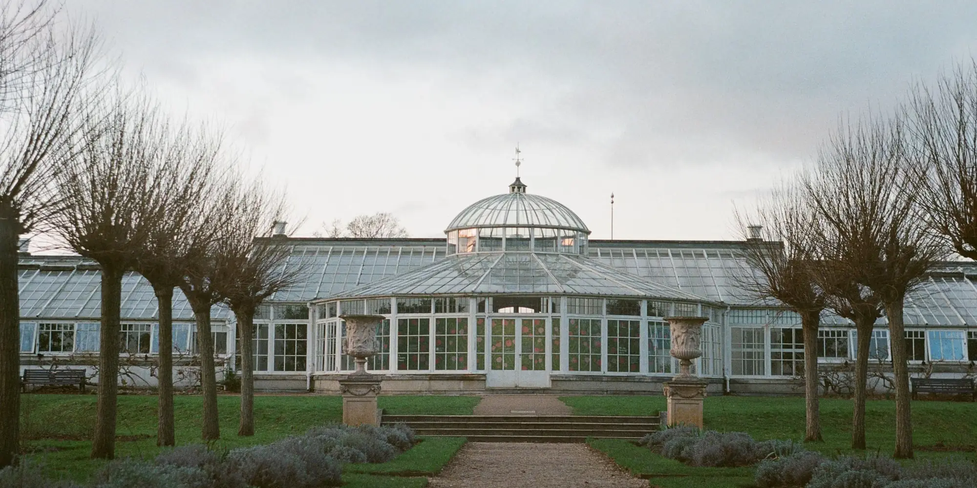 Long Victorian glasshouse with a pitched glass roof in a formal garden