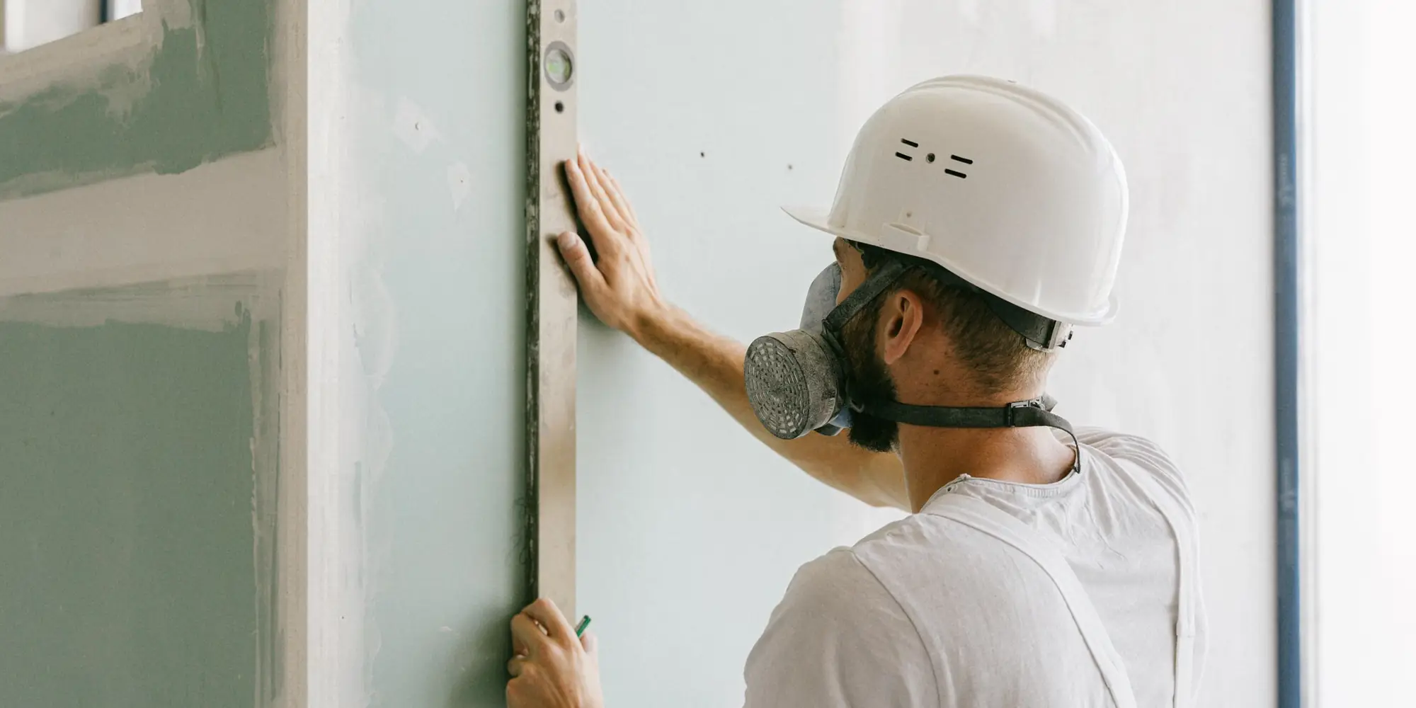 Checking a boarded wall for plumb with a long level