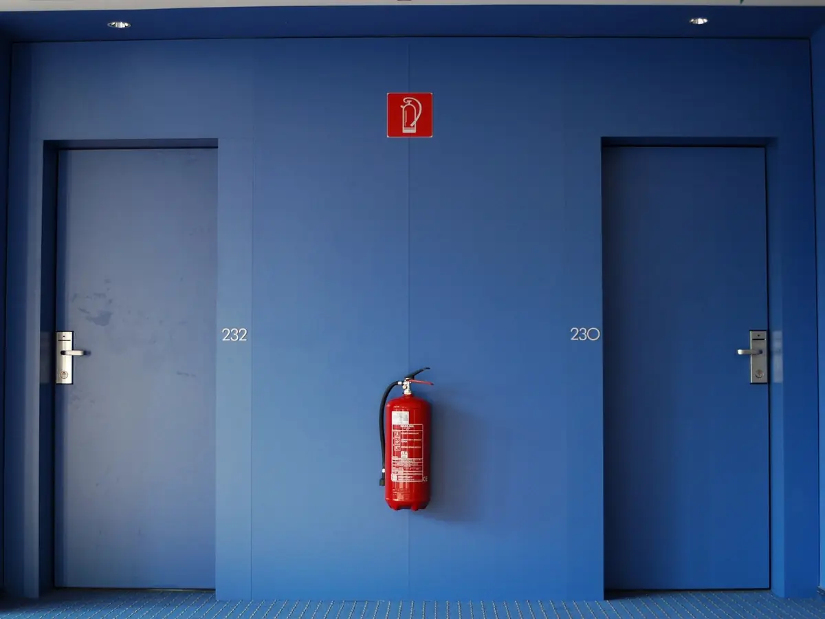 Blue fire doors either side of a wall-mounted extinguisher