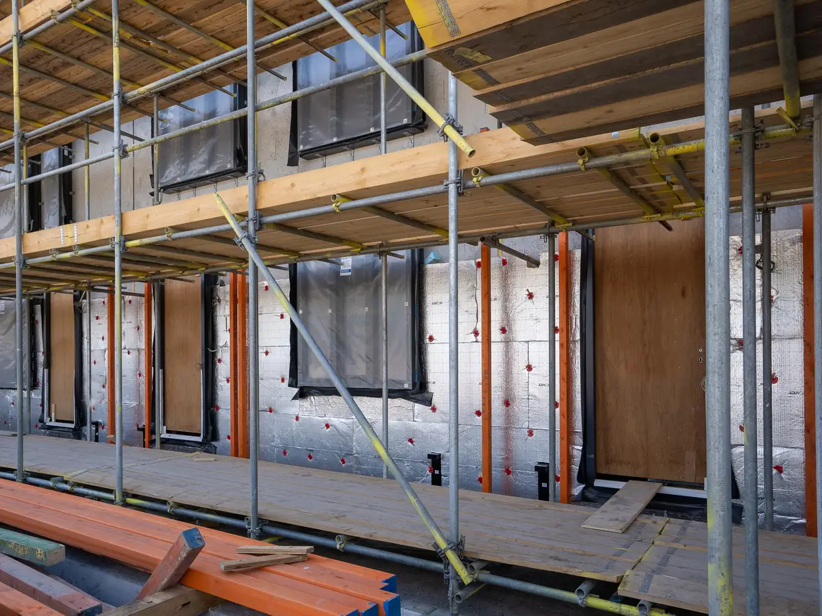 Insulation boards fixed to a house wall behind scaffolding before rendering