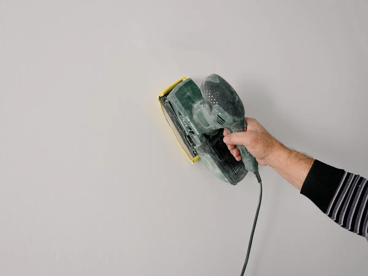Sanding back a filled wall before the final coat of plaster
