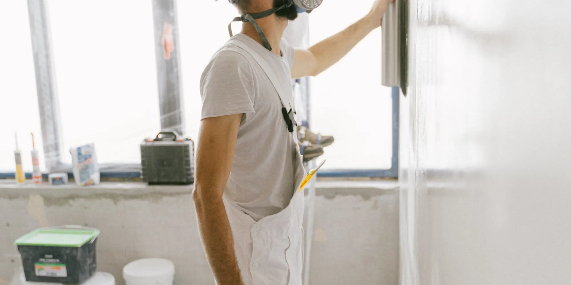 Two plasterers in masks skimming a large internal wall
