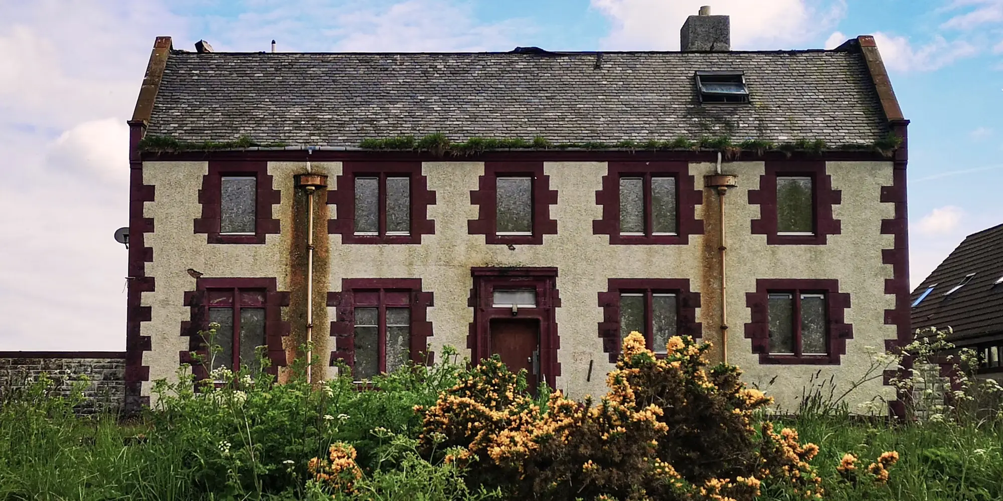 Rendered stone house with a slate roof and painted window surrounds
