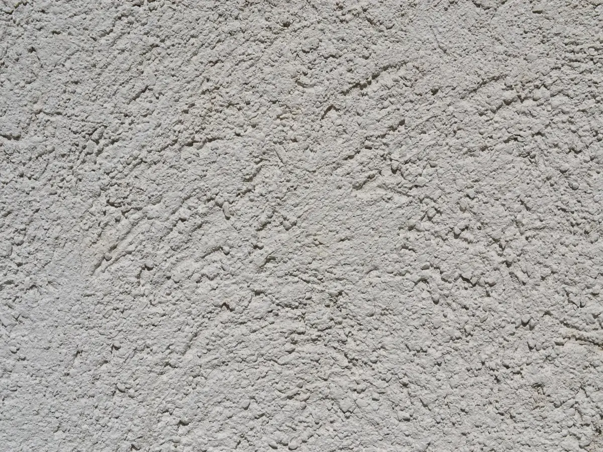 Close view of a light grey rendered wall with a fine scraped texture